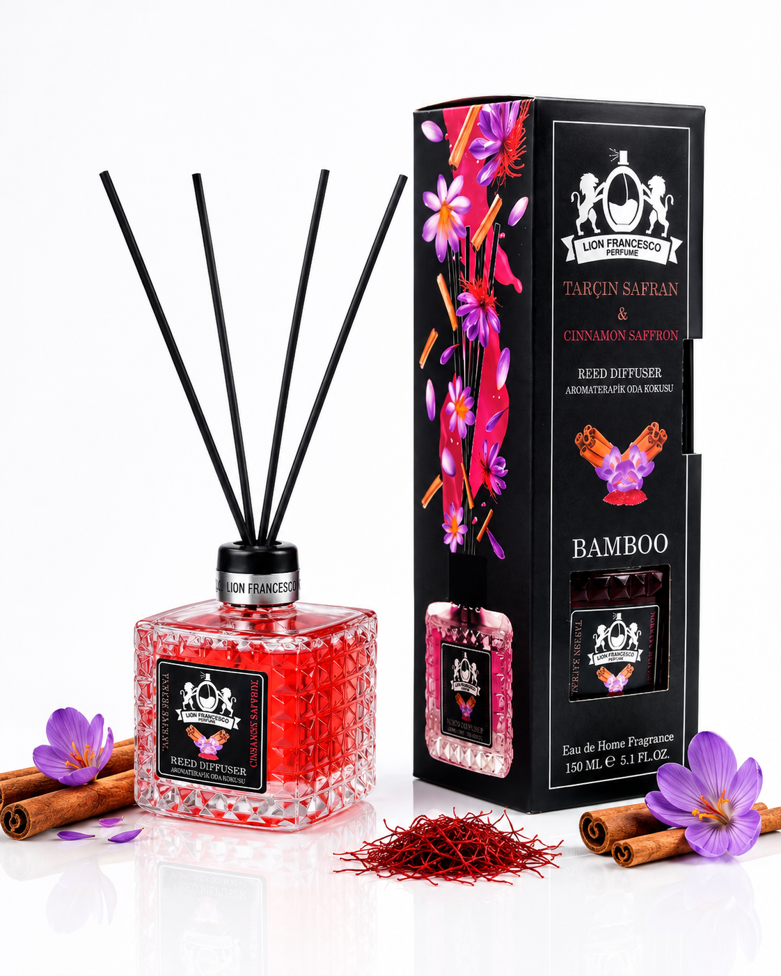 A reed diffuser bottle with a textured pink-red glass body, black reeds, and a black label, shown next to its tall black retail box with floral artwork. The scene is styled with cinnamon sticks, purple flowers, and red reed threads on a clean white background.