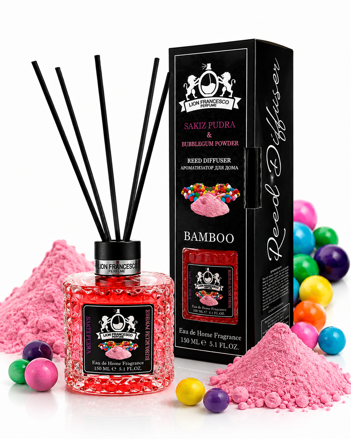 A reed diffuser bottle filled with pink sugar-like beads stands beside its black branded box, surrounded by pink powder piles, colorful candy-like balls, and diffuser reeds on a clean white background.