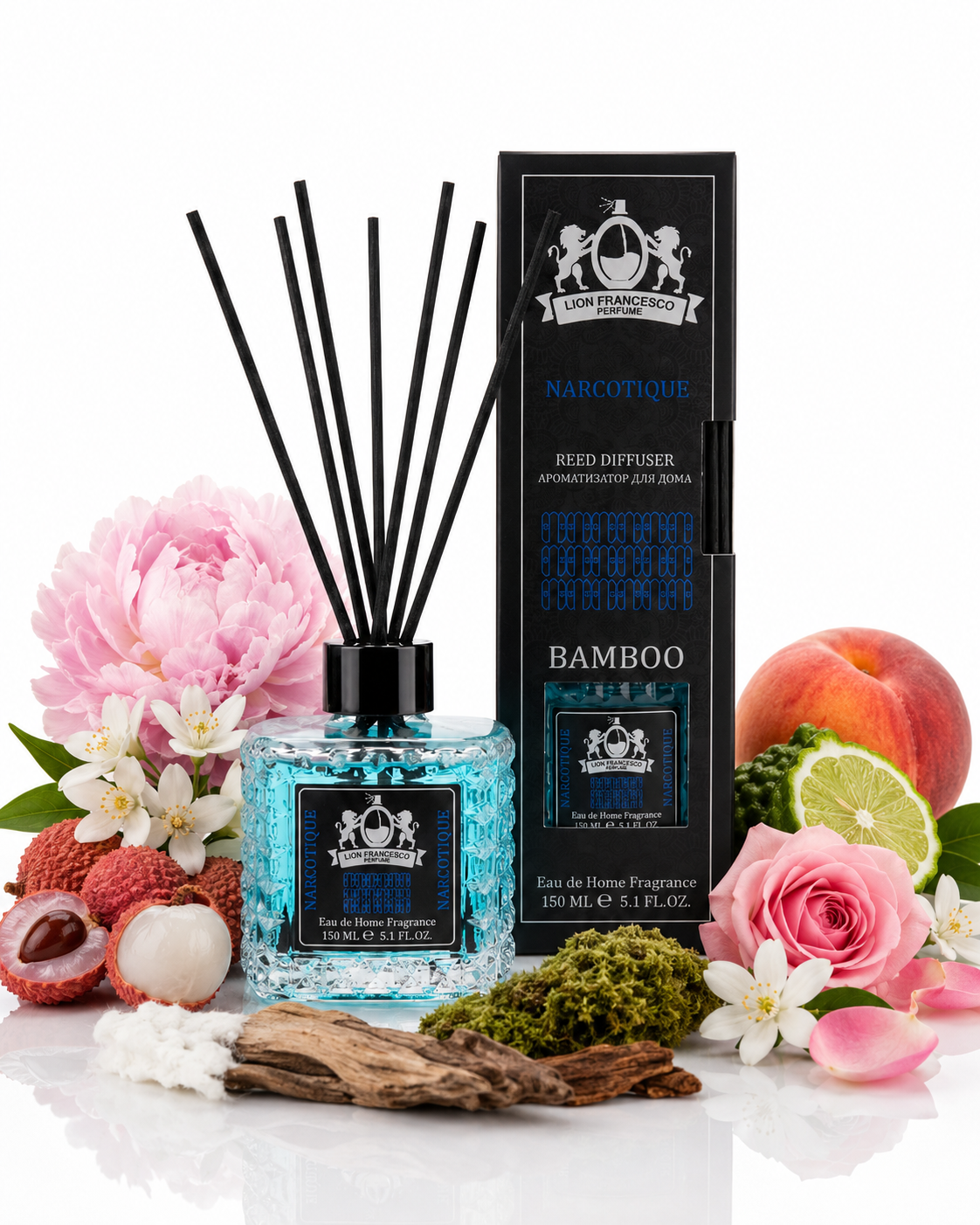 A reed diffuser bottle with blue liquid and black reeds stands beside its black branded box on a white studio background, surrounded by decorative botanical props including pink flowers, a peach, lychee, lime, moss, bark, and cotton. The packaging and bottle labels show the Narcotique Bamboo fragrance name and crest-style branding.